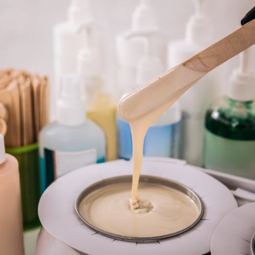wax in a wood spatula dripping in wax mixture bowl for hair removal treatment