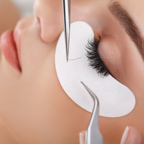 woman having eyelash treatment and extension with tweezers
